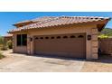 Attached garage door with decorative windows and stone trim, set against a desert backdrop at 20670 N 41St Ave, Glendale, AZ 85308