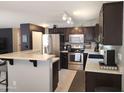 Modern kitchen featuring dark cabinets, stainless steel appliances, and a breakfast bar at 2317 E Mohave Ln, Apache Junction, AZ 85119