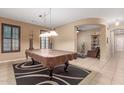 Spacious game room with a billiard table, neutral walls, and an adjacent living area with an arched entry at 16259 W Papago St, Goodyear, AZ 85338