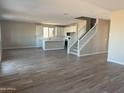Open-concept living space with wood-look floors seamlessly connecting the living area, kitchen, and staircase at 22863 N 183Rd Dr, Surprise, AZ 85387