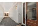 Well-lit hallway entrance featuring elegant lighting, carpet flooring, and a stylish wooden door at 4909 N Woodmere Fairway -- # 1004, Scottsdale, AZ 85251