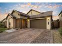 Charming single-story home with stone accents, a tile roof, manicured lawn and a brick paver driveway at 6954 W Maya Way, Peoria, AZ 85383