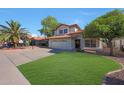 Charming two-story home boasting a red tile roof, well-manicured lawn, and desert landscaping with a palm tree at 7658 W Boca Raton Rd, Peoria, AZ 85381