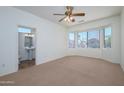 Comfortable bedroom with a large window, neutral carpet and an attached bath with a pedestal sink at 18651 N Salerno Ct, Surprise, AZ 85387