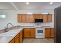 Functional kitchen with wooden cabinets, white appliances, and a stainless steel microwave at 18651 N Salerno Ct, Surprise, AZ 85387