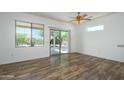 Bright, open living room featuring wood-look floors, neutral walls, and a sliding glass door at 18651 N Salerno Ct, Surprise, AZ 85387
