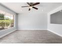 Bright living room with wood-look tile flooring, a ceiling fan, and a large window for natural light at 3126 W Stella Ln, Phoenix, AZ 85017