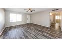 Spacious living room featuring wood flooring, a ceiling fan, and natural light from a large window at 4833 N 63Rd Ln, Phoenix, AZ 85033