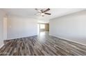 Bright living room showcasing wood flooring, a ceiling fan, and a seamless flow to the kitchen at 4833 N 63Rd Ln, Phoenix, AZ 85033