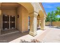 Charming stucco facade with arched entryway, offering a glimpse of the tile flooring of the front porch at 9797 N 100Th Pl, Scottsdale, AZ 85258