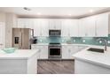 Kitchen featuring stainless steel appliances, teal backsplash, white cabinets, and stone countertops at 2511 W Queen Creek Rd # 258, Chandler, AZ 85248
