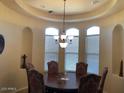 Elegant dining room featuring a tray ceiling, chandelier lighting, and large windows at 35401 N Via Tramonto St, Phoenix, AZ 85086