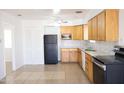 Functional kitchen featuring wood cabinets, black appliances, and neutral tile flooring at 3651 W Mariposa St, Phoenix, AZ 85019