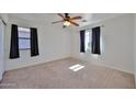 Spacious bedroom with carpet, a ceiling fan, and two windows offering natural light at 6843 S 9Th Ave, Phoenix, AZ 85041