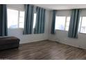 Bright living room with new wood flooring and large windows dressed with teal curtains at 7807 E Main St # D-26, Mesa, AZ 85207