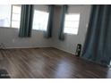 Bright living room featuring modern wood flooring and many windows dressed with teal curtains at 7807 E Main St # D-26, Mesa, AZ 85207