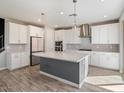 Spacious kitchen with white cabinets, center island, and modern pendant lighting at 10013 E Trent Ave, Mesa, AZ 85212