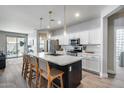 Elegant kitchen boasts a central island with barstool seating, stainless steel appliances and white cabinetry at 12211 W Hide Trl, Peoria, AZ 85383