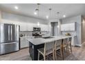 Modern kitchen with stainless steel appliances, a large center island with seating, and stylish pendant lighting at 12211 W Hide Trl, Peoria, AZ 85383