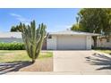 Home exterior featuring a two-car garage, a desert landscaped yard with a large cactus, and a decorative gate at 12826 W Maplewood Dr, Sun City West, AZ 85375