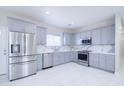 Well-lit kitchen showcasing stainless steel appliances, grey cabinets, quartz countertops, and ample counter space at 12940 W Tara Ln, Surprise, AZ 85374
