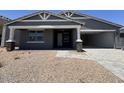 Charming single-story home with gray siding, stone accents, and a welcoming covered porch leading to an open garage at 15794 W Cheryl Dr, Waddell, AZ 85355