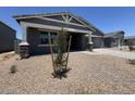 View of a charming gray single-story home with a covered porch and gravel landscaping, complemented by a blue sky at 15794 W Cheryl Dr, Waddell, AZ 85355