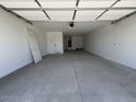 A spacious, clean garage featuring white walls, a concrete floor, and a door leading to the interior of the home at 15794 W Cheryl Dr, Waddell, AZ 85355