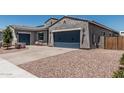 Stucco home featuring a large garage, desert landscaping, and a paved driveway at 17980 W Meadowbrook Ave, Goodyear, AZ 85395