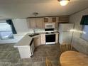 Functional kitchen featuring light wood cabinetry, modern appliances, and a cozy dining area at 201 S Greenfield Rd # 118, Mesa, AZ 85206
