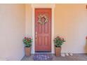 Welcoming front door with a wreath, flanked by potted plants and decorative stone accents at 22851 S 229Th Pl, Queen Creek, AZ 85142