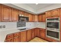 Well-lit kitchen with wood cabinetry, stainless steel appliances, white countertops and a glass tile backsplash at 4212 W Tierra Buena Ln, Phoenix, AZ 85053