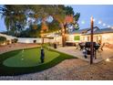 Beautiful backyard with putting green, outdoor seating, string lights, and mature trees perfect for entertaining at 5338 E Hearn Rd, Scottsdale, AZ 85254