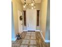 Inviting foyer featuring decorative tile, wood flooring, and an elegant light fixture at 7313 S 25Th S Dr, Phoenix, AZ 85041
