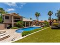 Expansive backyard featuring a pool, patio, artificial turf, and lush landscaping at 18854 N 73Rd Dr, Glendale, AZ 85308
