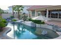 Tranquil backyard pool with rock waterfall feature, surrounding greenery and shade umbrella at 2053 E Clubhouse Dr, Phoenix, AZ 85048