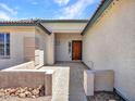 Welcoming covered entrance with a concrete path, desert landscaping, and textured exterior walls at 10501 W Wilshire Dr, Avondale, AZ 85392