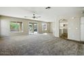 Spacious living room featuring neutral walls, carpet flooring, ceiling fan, and abundant natural light at 118 N 223Rd Ave, Buckeye, AZ 85326