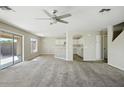 Bright and airy living room featuring neutral walls, carpet flooring, ceiling fan, and access to the backyard at 118 N 223Rd Ave, Buckeye, AZ 85326