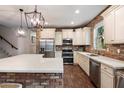 Bright and well-equipped kitchen with white cabinets, stainless steel appliances, and brick accent wall at 3944 W Paradise Ln, Phoenix, AZ 85053