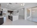 Open-concept kitchen and living area with white tiled floors, a large center island, and a modern staircase at 5917 N 83Rd Ln, Glendale, AZ 85305