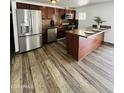 Modern kitchen featuring stainless steel appliances, wood cabinets, and a granite countertop breakfast bar at 7135 W Heatherbrae Dr, Phoenix, AZ 85033