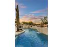 Lush backyard pool with serene waterfall feature, rock details, mature cacti and desert plantings under an open sky at 7315 E Brisa Dr, Scottsdale, AZ 85266