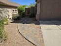 Brick-paved walkway leading to a gated side yard with gravel landscaping next to garage at 7722 E Wolf Canyon St, Mesa, AZ 85207