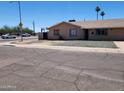 Quaint single-story home with xeriscaped front yard, complemented by mature palm trees against a clear blue sky at 1602 N 57Th Ave, Phoenix, AZ 85035