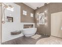 Modern bathroom with a standalone tub, tiled walls, and unique lighting fixtures at 2129 E Beautiful Ln, Phoenix, AZ 85042