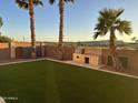 Private backyard oasis featuring artificial grass, a built-in grill, and mature palm trees at 28306 N 25Th Dl, Phoenix, AZ 85085