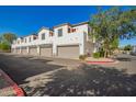 Townhome exterior featuring multiple car garages, white stucco, and red window frames at 3150 E Beardsley Rd # 1081, Phoenix, AZ 85050