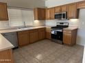 Well-lit kitchen features stainless steel appliances, wooden cabinetry, and neutral countertops, perfect for cooking at 45091 W Gavilan Dr, Maricopa, AZ 85139