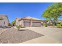 Side view of a beige single-story house, featuring a three-car garage, desert landscaping, and a tile roof at 694 W Beechnut Dr, Chandler, AZ 85248